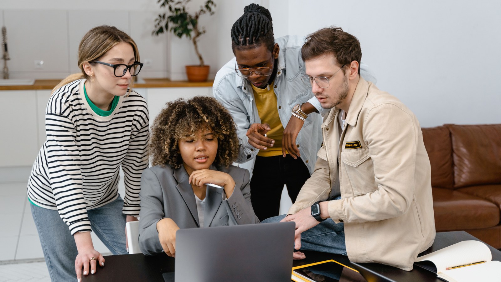 A small team gathered around a laptop, reviewing a plan together